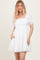 woman wearing a white short puff sleeve dress with a square neckline and pockets