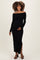 woman wearing a black off-the-shoulder ribbed maternity dress with a side slit and holding her baby bump