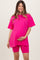woman wearing a bright pink oversized maternity t-shirt and matching bike shorts, holding her baby bump