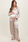 woman wearing a light beige satin maternity pajama set and holding her baby bump