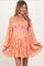 woman wearing a pink floral maternity dress with long sleeves and a flared skirt
