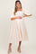 woman wearing a cream puff sleeve maternity dress with floral embroidery and a baby bump