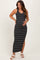 woman wearing a black and white striped maternity maxi dress with a side slit and holding her baby bump