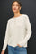 woman wearing a cream long sleeve henley top with three buttons and a relaxed fit paired with blue jeans