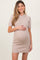 woman wearing a short sleeve taupe maternity dress and gently holding her baby bump