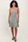 woman wearing a gray and white striped spaghetti strap skater dress with a flared skirt and black heeled sandals