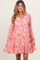 woman wearing a pink floral maternity dress with long sleeves and a tiered skirt, smiling at the camera