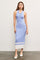 woman wearing a light blue ribbed midi dress with buttons and white accents, standing on a textured floor