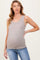 woman wearing a beige ribbed maternity tank top and showing her baby bump, paired with denim jeans