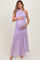 woman wearing a purple one-shoulder maternity gown with a flowing skirt and holding her baby bump