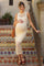 woman wearing a cream knitted maternity midi dress and holding her baby bump while standing on decorative tiled steps