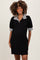woman wearing a black maternity polo dress with stripe puff sleeves and a buttoned collar, smiling and showing her baby bump