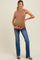 woman wearing a tan ribbed maternity tank top and blue flared jeans, holding her baby bump