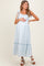 woman wearing a light blue striped maternity dress with tie straps and a visible baby bump