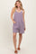 woman wearing a purple striped sleeveless romper with side pockets and a relaxed fit