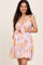 woman wearing a pink and yellow floral maternity dress with a tie-front and bubble hem, holding her baby bump
