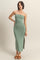 woman wearing a sage green strapless midi dress with a side slit and a fitted silhouette