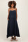 woman wearing a navy blue maternity maxi dress with adjustable straps and pockets, featuring a ruffled hem and visible baby bump