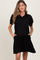 woman wearing a black short sleeve maternity dress with a collar and side pockets, showing a baby bump