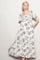 woman wearing a white floral print maxi dress with puff sleeves and a ruffled hem.