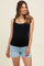 woman wearing a black maternity tank top and denim shorts, showing a visible baby bump