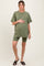 woman wearing a short sleeve olive green maternity t-shirt and matching bike shorts, holding her baby bump