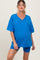 woman wearing a bright blue maternity oversized v-neck t-shirt and matching bike shorts with a visible baby bump