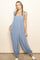 woman wearing a blue floral jumpsuit with ruffle straps and relaxed fit, styled with braids in her hair