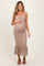 woman wearing a beige ribbed maternity dress with a tie detail and ruffled hem, holding her baby bump.