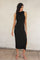 woman wearing a black ribbed sleeveless midi dress with a side slit and strappy heels