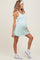 woman wearing a light mint green maternity dress with a fitted bodice and flared skirt, showing her baby bump