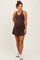 woman wearing a dark brown maternity tank dress with a visible baby bump and styled with white sneakers