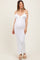 woman wearing a white off-the-shoulder maternity dress with ruffle details and a visible baby bump