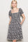 woman wearing a black floral puff sleeve dress with a square neckline and pockets