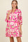 woman wearing a pink and white floral maternity dress with a relaxed fit and three-quarter sleeves