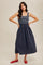 woman wearing a navy and white striped maxi dress with a fitted bodice and flared skirt, styled with red flats