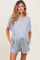 woman wearing a gray maternity romper with short sleeves and a drawstring waist, showing a baby bump