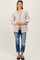 woman wearing a beige striped maternity cardigan over a brown top and blue distressed jeans, smiling at the camera