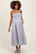 woman wearing a striped maternity dress with a smocked bodice and pockets, smiling with hair in loose curls