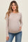 woman wearing a beige long sleeve maternity top and holding her baby bump
