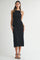 woman wearing a black midi dress with a wavy texture and a halter neckline, standing in a neutral background