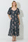 woman wearing a navy floral maxi dress with puff sleeves and pockets, standing against a light backdrop