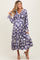 woman wearing a purple floral maternity dress with long sleeves and a flowy skirt, showcasing her baby bump