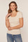 woman wearing a light beige short sleeve scoop neck top with a fitted style and smiling