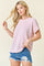 woman wearing a light pink ribbed short sleeve top paired with distressed denim shorts