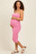 woman wearing a pink strapless maternity dress with a visible baby bump and white sandals