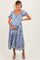 woman wearing a blue floral maternity maxi dress, holding her baby bump and smiling