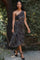 woman wearing a brown leopard print one-shoulder dress with a side cutout and draped detail, walking outdoors