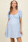 woman wearing a blue gingham maternity dress with puff sleeves and a fitted bodice, showing her baby bump