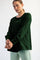 woman wearing a dark green long sleeve top with a relaxed fit and raglan sleeves